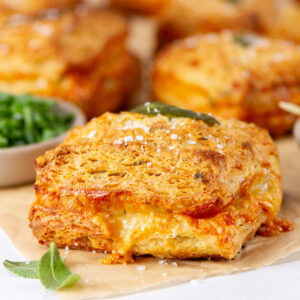 square crop of some biscuits on parchment paper with sage leaves and chives around them.