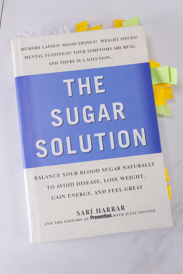 The Sugar Solution book on a white background with several sticky note tabs sticking out.