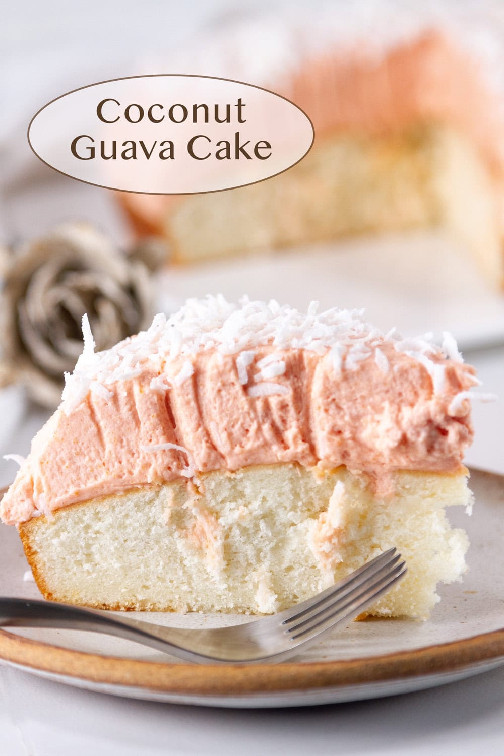 a slice of coconut cake topped with guava frosting and a fork next to it.
