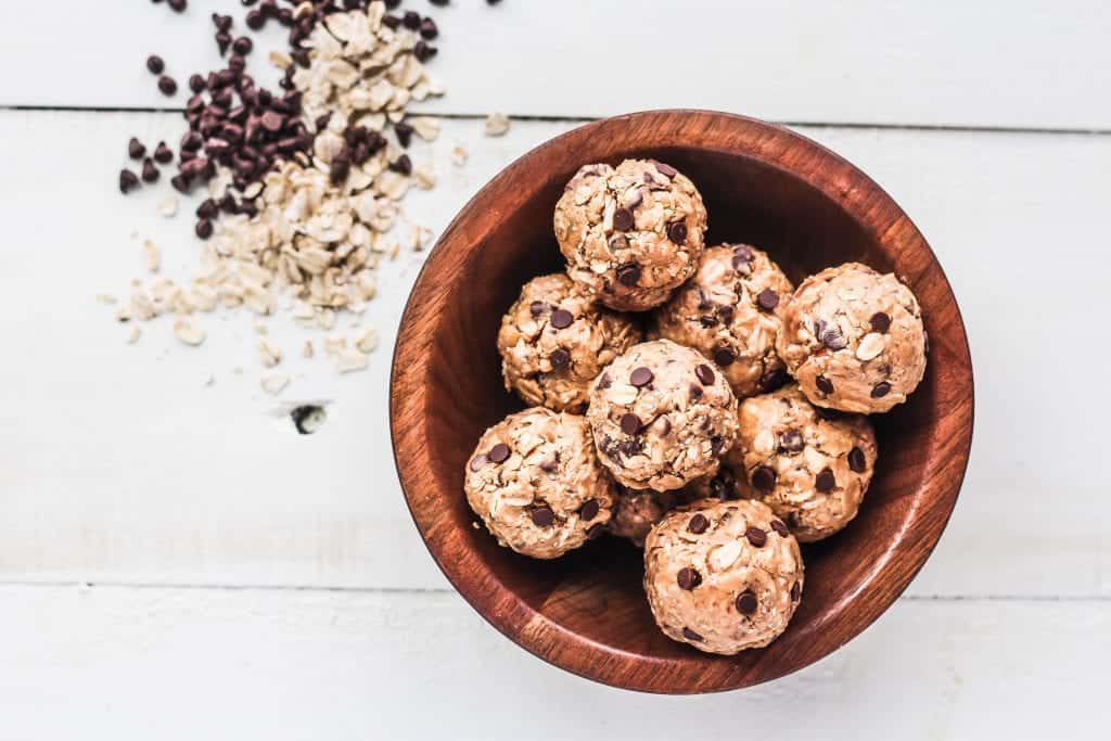a bowl filled with protein bites and chocolate chips and oats next to the bowl.