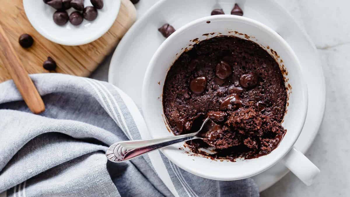 looking down into a chocolate cake baked in a mug with a spoon in it.