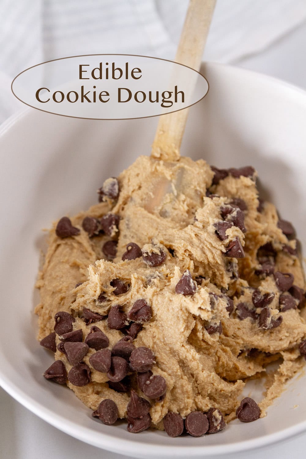 A bowl filled with chocolate chip cookie dough and a spatula in the dough.