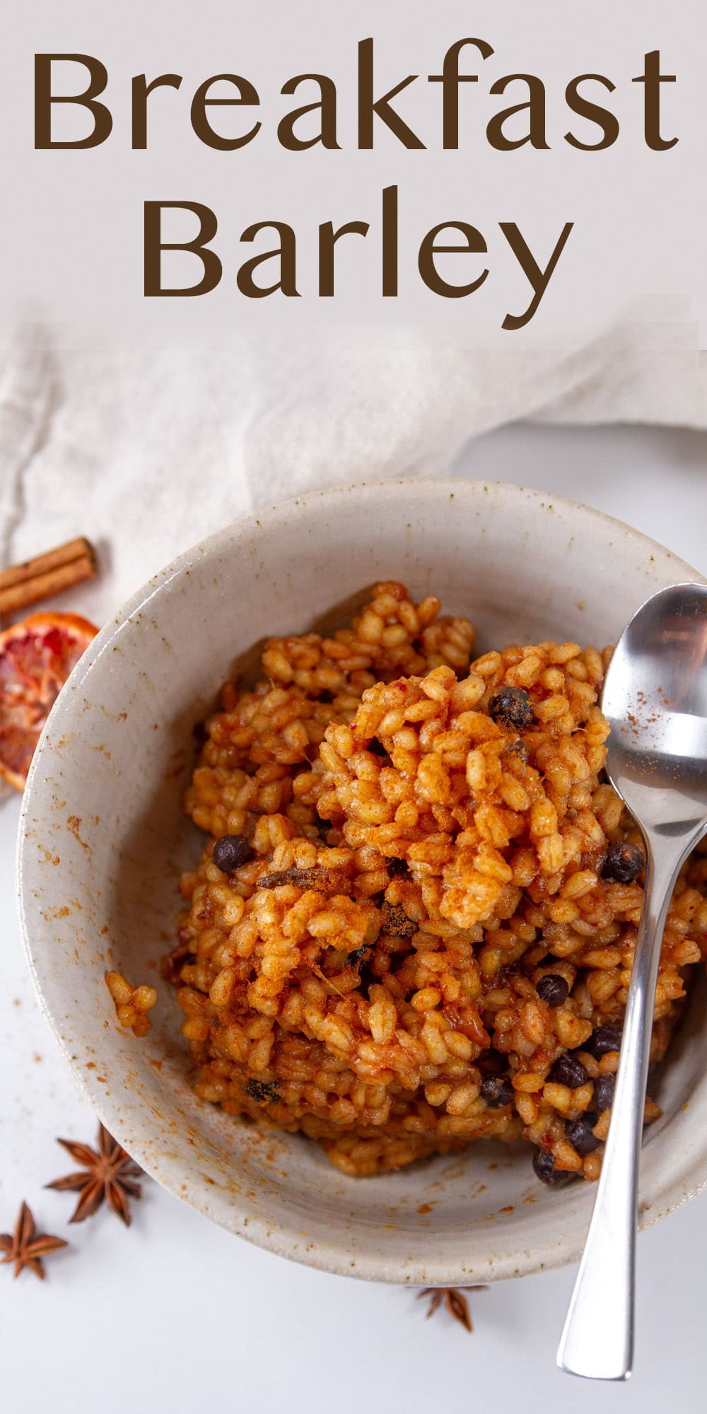 a bowl of cooked barley with a spoon and some spices around the bowl.