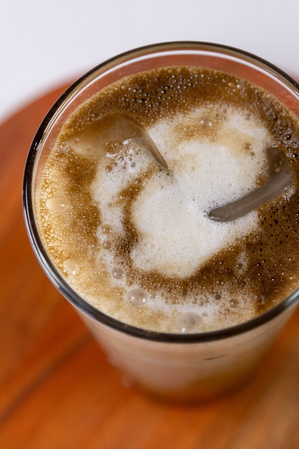 looking down into an iced latte on a wooden background.