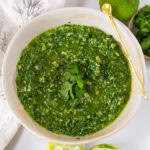 square crop looking into a bowl filled with pesto sauce garnished with cilantro.