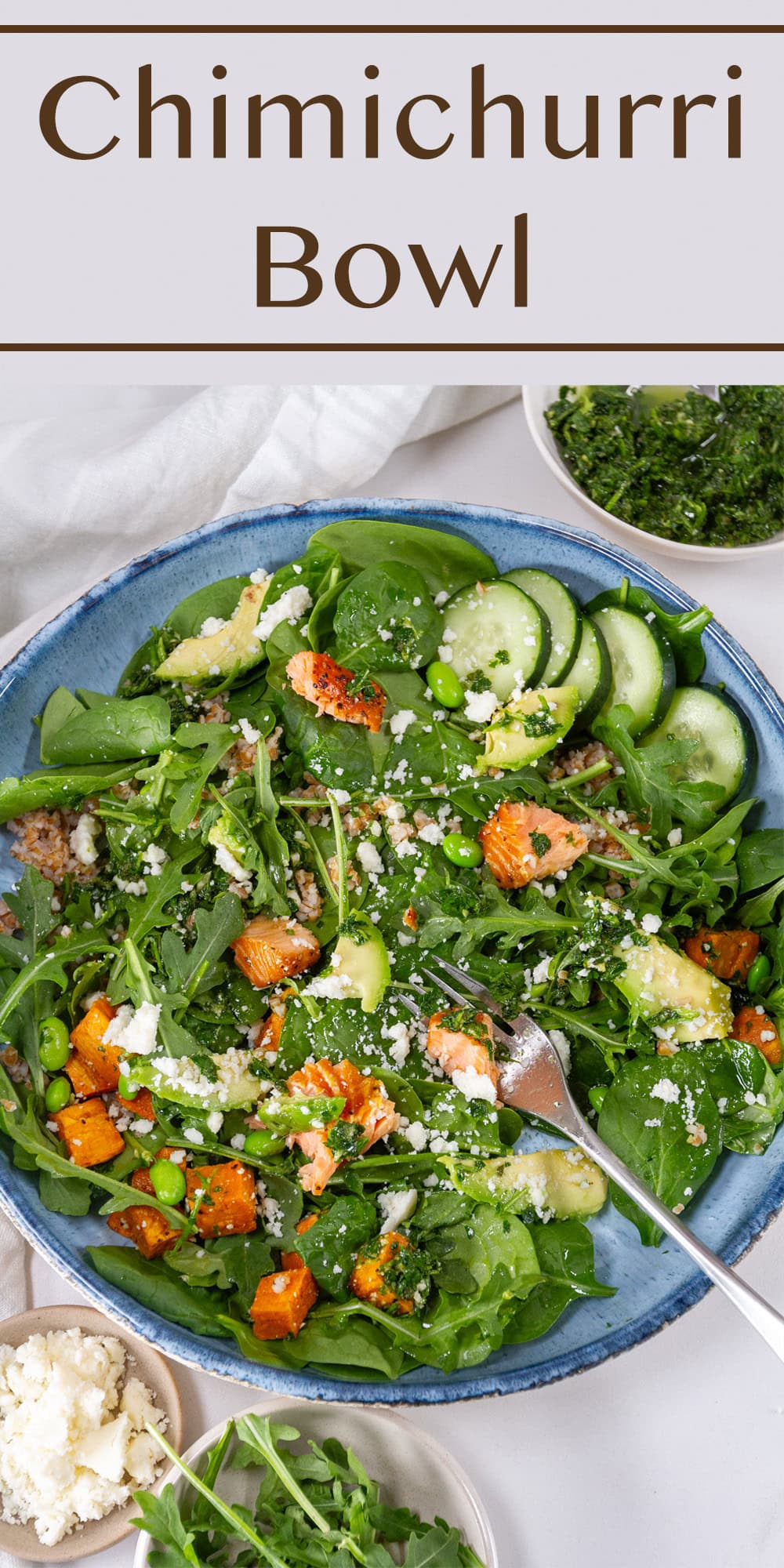 a large blue bowl filled with veggies, salmon, cheese, and chimichurri sauce and a fork in the lower right.