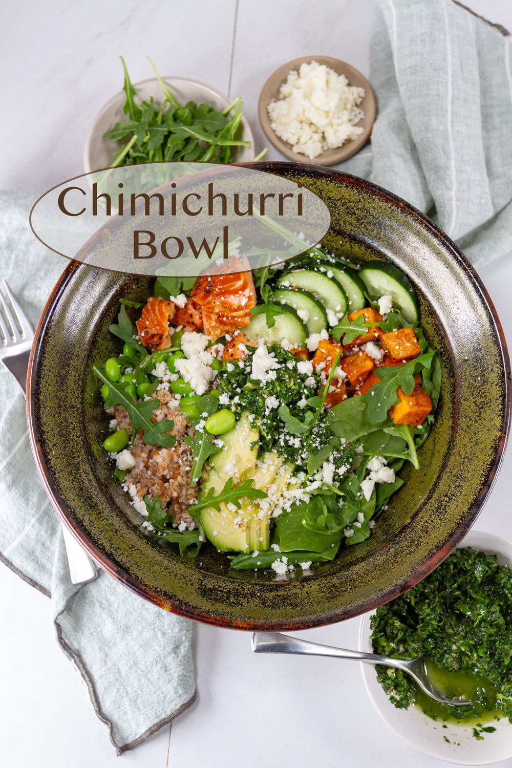 looking down into a green dark green bowl with a big salad in it and some small bowls around it.