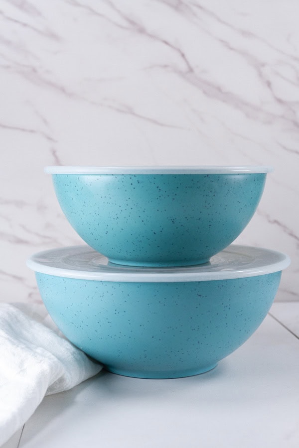 two large blue bowls with lids stacked on top of each other.