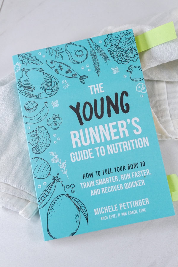 a book, The Young Runner's Guide to Nutrition: How to Fuel Your Body to Train Smarter, Run Faster, and Recover Quicker, with post it note tabs sticking out of the pages.
