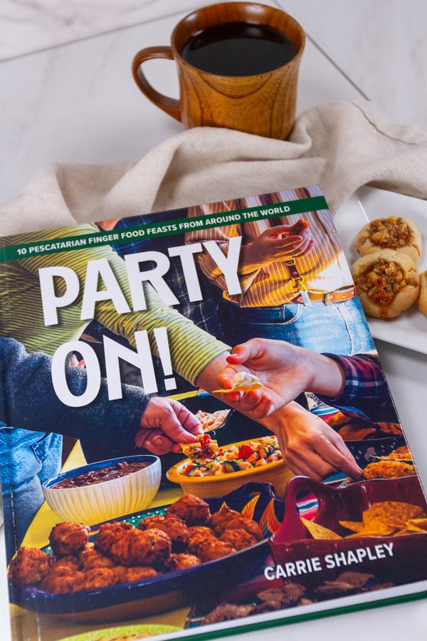 a cookbook, Party On, with a cup of coffee and some cookies.