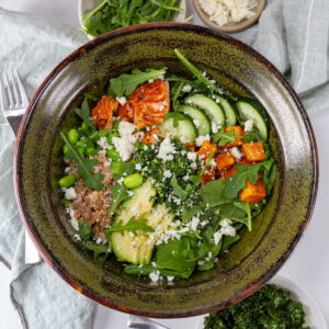 square crop looking down into a chimichurri bowl with veggies, cheese, salmon and a fork to the left.