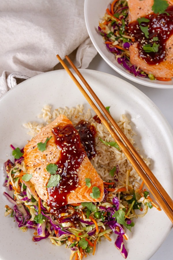 two salmon bowls one has chopsticks on the right side.