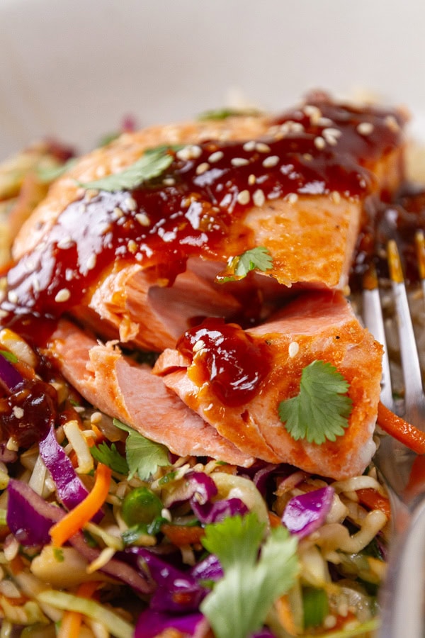 a cooked piece of salmon with sauce over the top and a fork next to it.