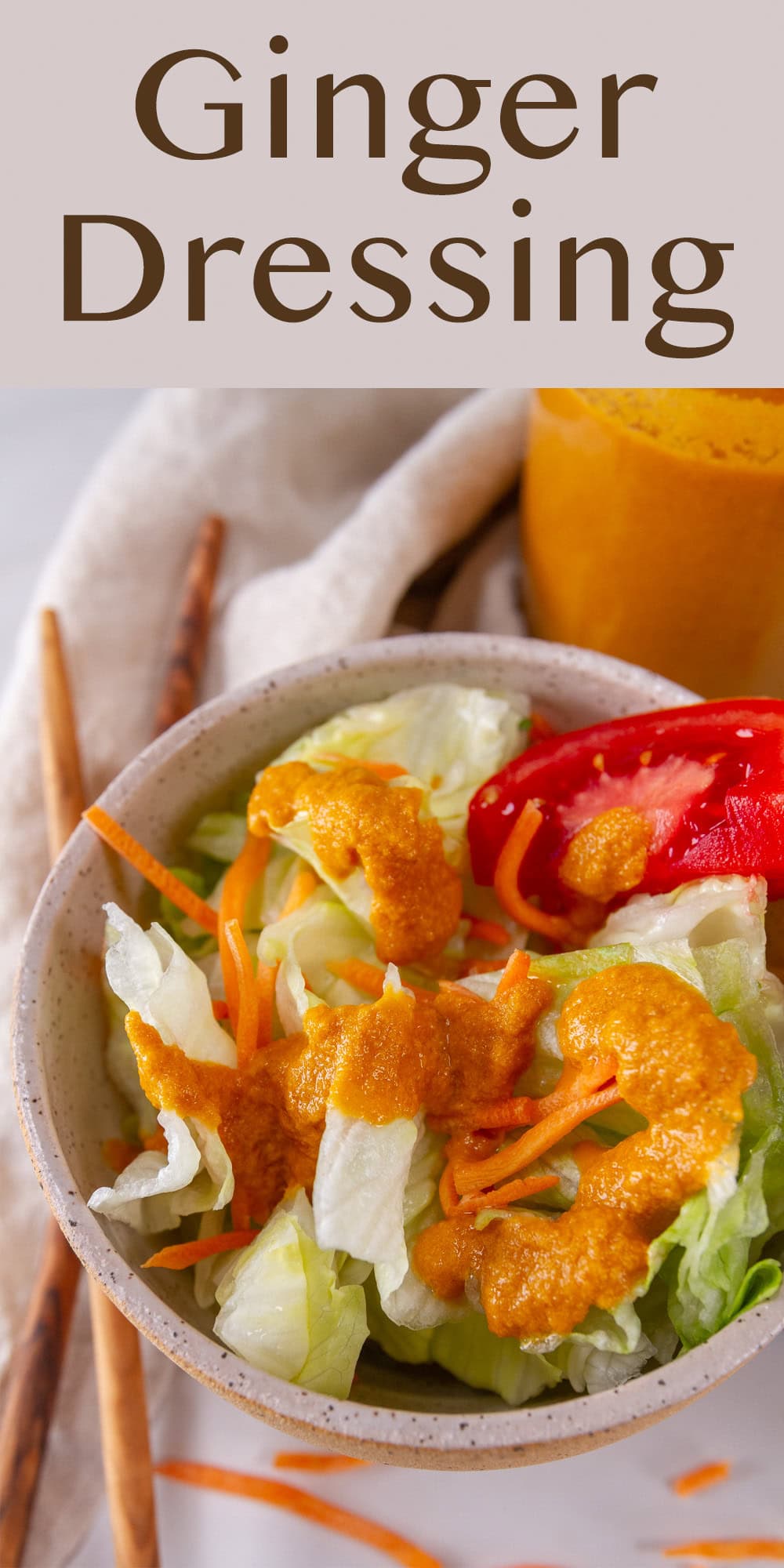 a salad in a small bowl topped with orange dressing and chopsticks next to the bowl.