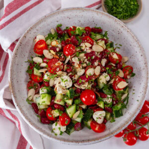 square crop of a white bowl filled with bean and vegetable salad.