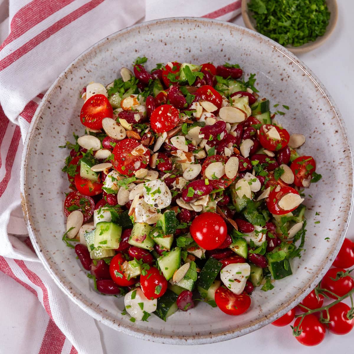 square crop of a white bowl filled with bean and vegetable salad.