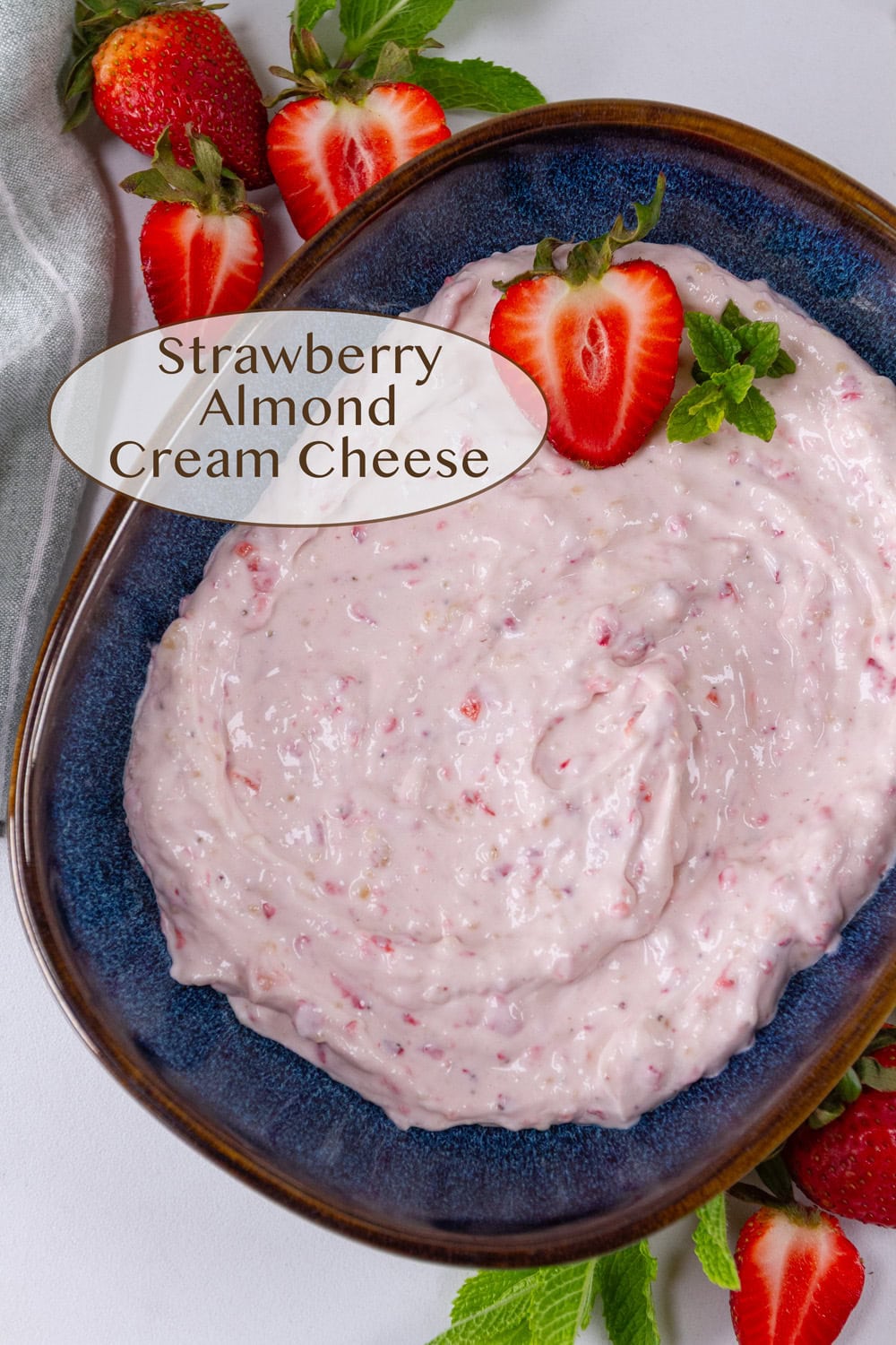 a blue bowl filled with strawberry cream cheese and some fresh strawberries around it.