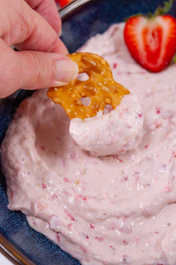 Dipping a pretzel into strawberry spread.