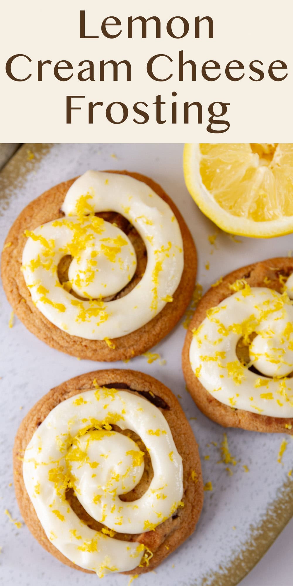 looking down onto 3 cookies with frosting and a cut lemon on the side.