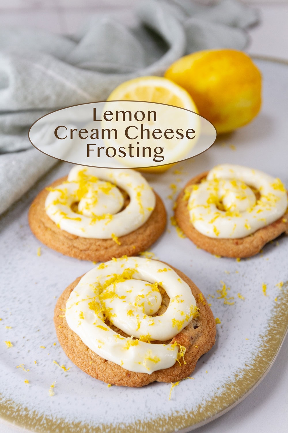 cookies on a tray with some lemons, and the cookies are topped with frosting.