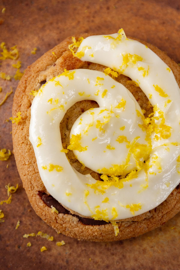 close up on a frosted cookie on a brown plate.