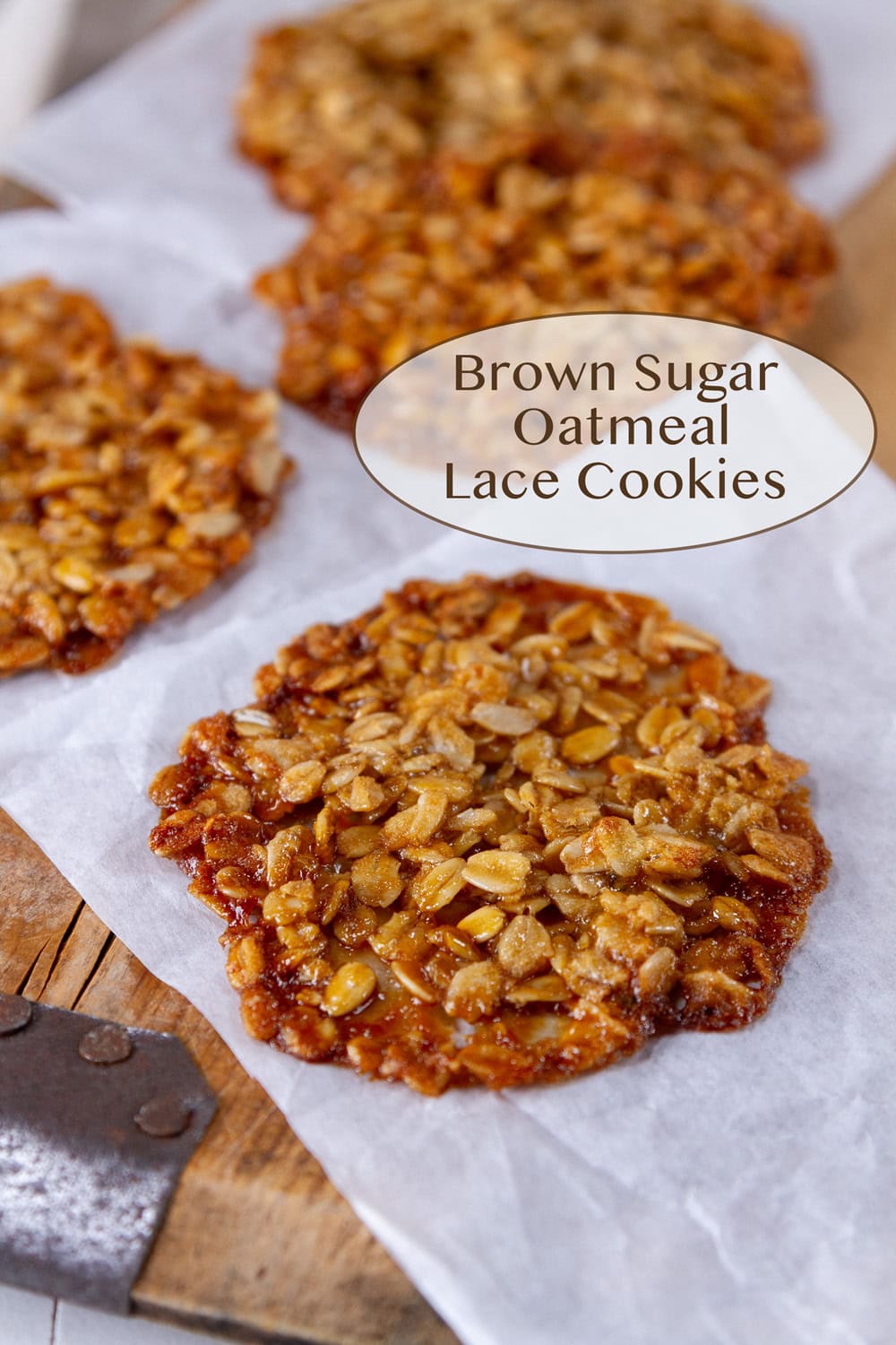 oatmeal lace cookies on parchment paper on a wooden serving tray.