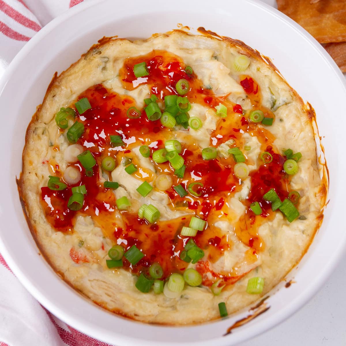 square cup of a baked crab Rangoon dip with sweet chili sauce.