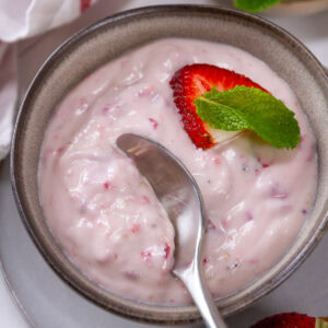square crop looking down into a bowl of pudding with a spoon in it.