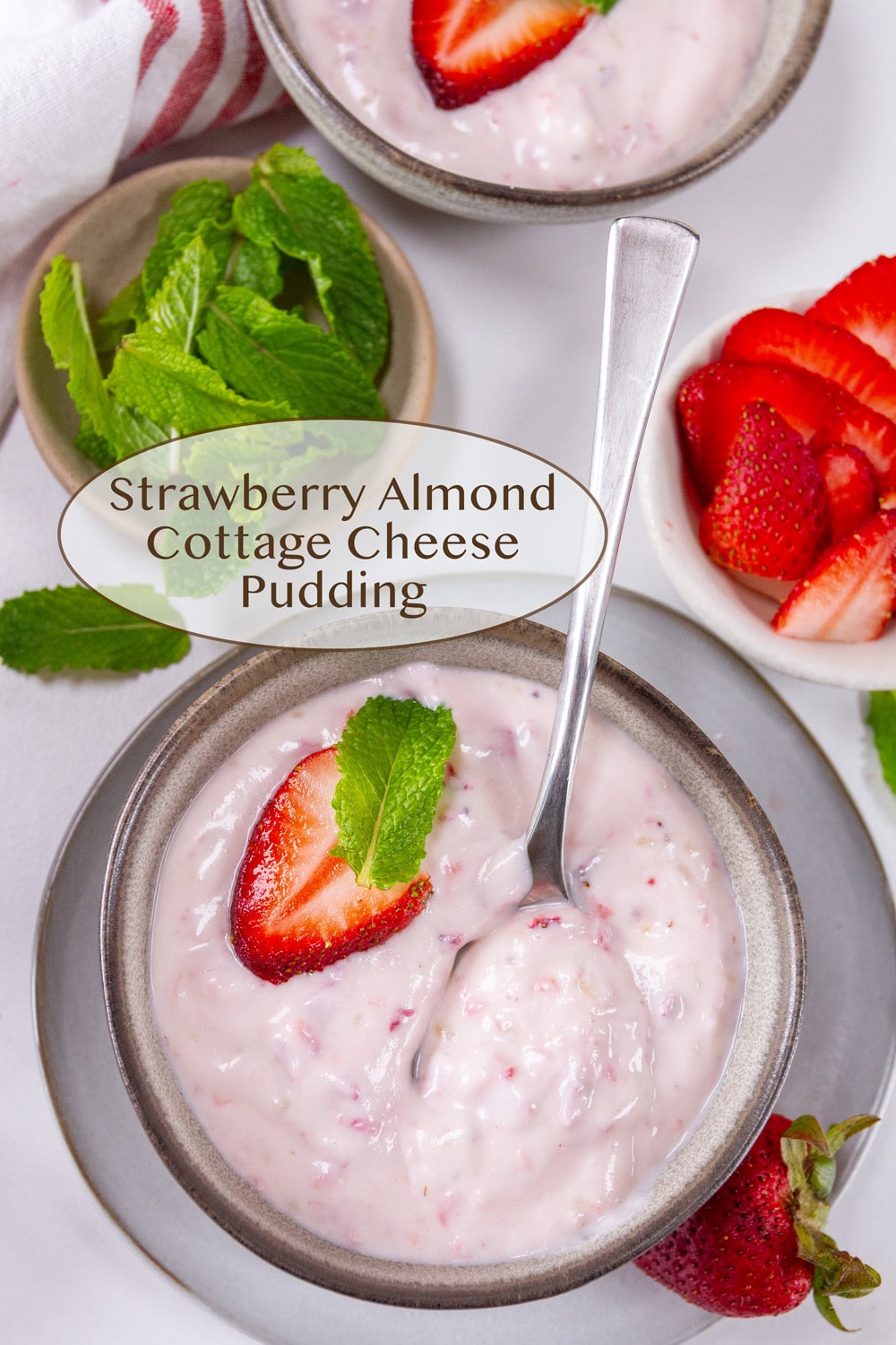 Looking down on two small bowls of strawberry pudding one with a spoon in it.