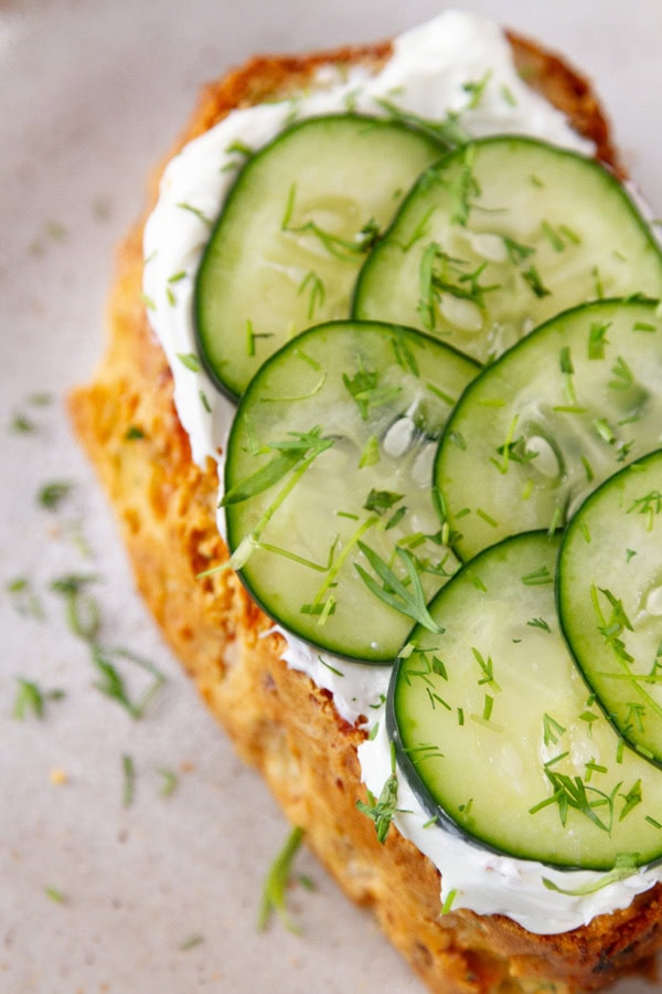 looking down on a slice of bread topped with cream cheese and cucumbers.