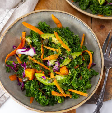 square crop of a bowl of kale salad with a fork to the right.