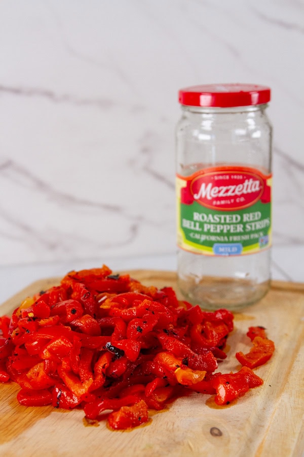 chopped roasted red peppers in front of the empty jar of peppers.