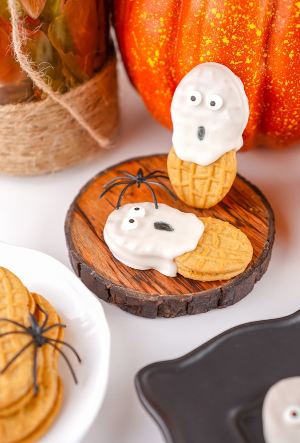 Ghost cookies in a fall setting with spiders and pumpkins.