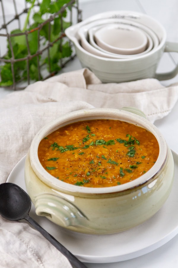 a small pot of soup with a spoon in front of some kitchen tools.