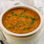square crop of a bowl of pumpkin soup in a light colored pot.