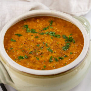 square crop of a bowl of pumpkin soup in a light colored pot.