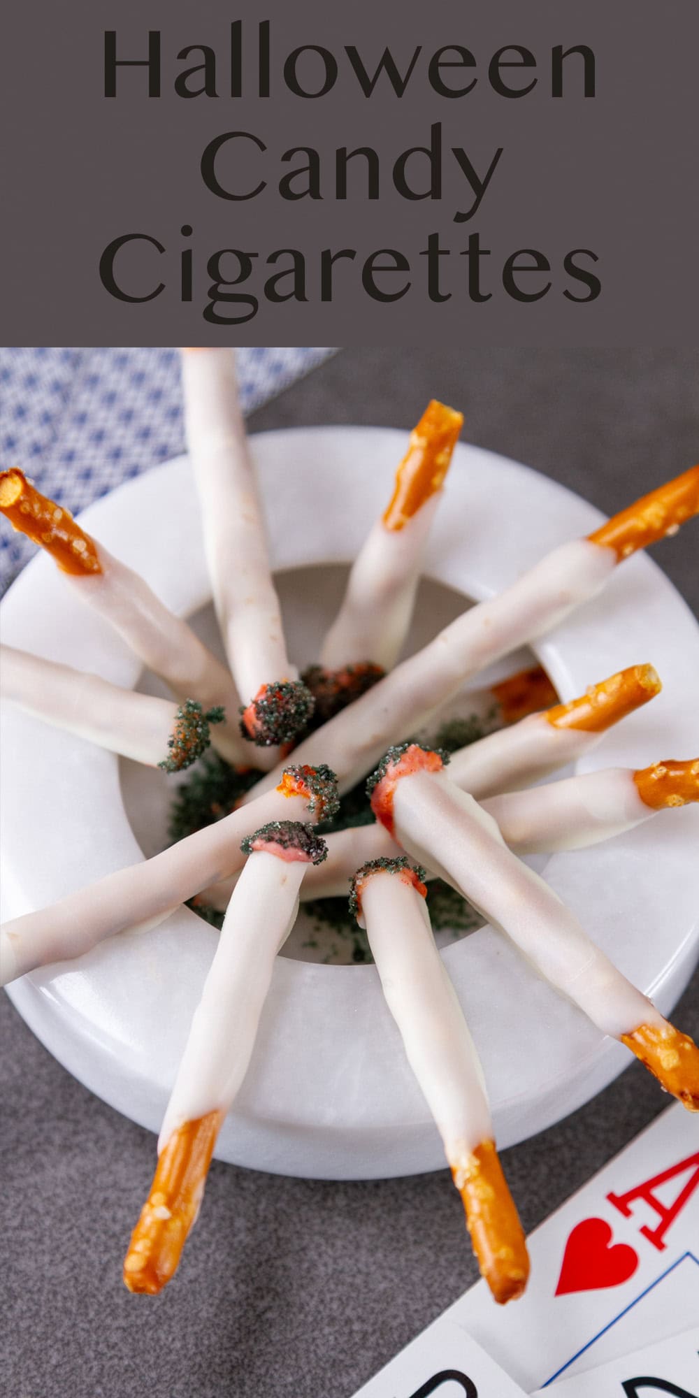 a white ash tray with candy cigarettes on it and playing cards around it.