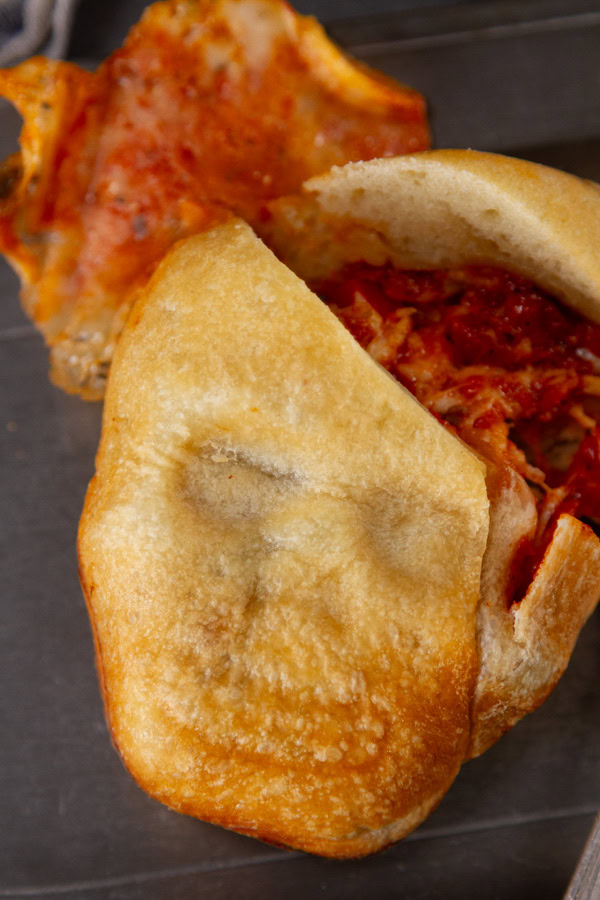 a baked pizza skull that's been cut open to reveal the fillings.