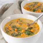 square crop of two bowls of soup, the one in front has a spoon in it.