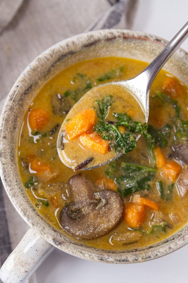 a soup mug of tahini soup and a spoon taking a bite out.