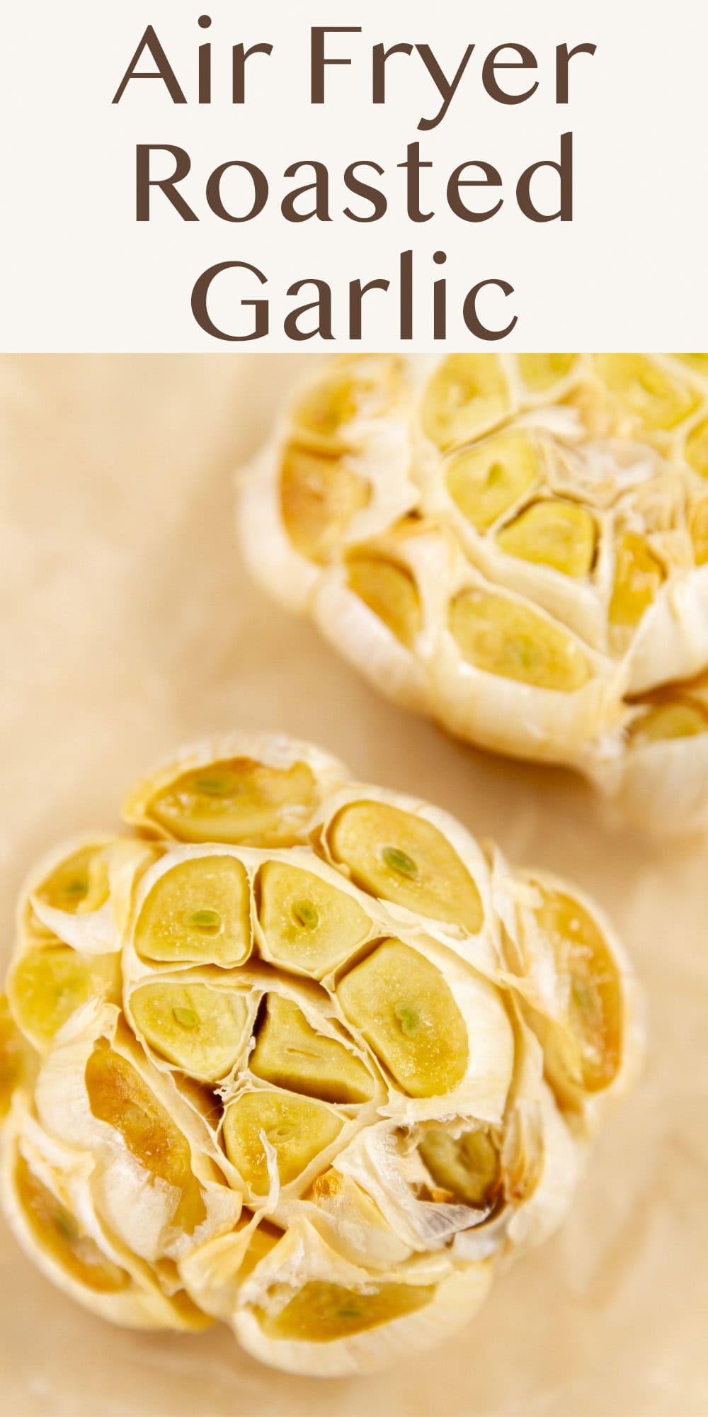 two heads of garlic that have been roasted on a piece of parchment paper.