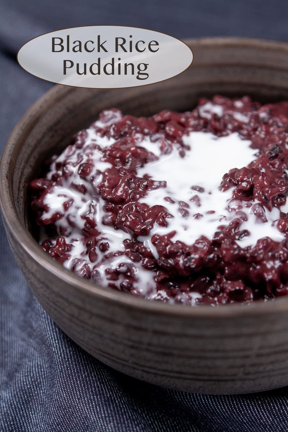 a dark colored bowl filled with black rice pudding topped with coconut milk.