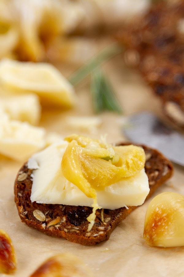roasted garlic on cheese and crackers on a cheese plate.