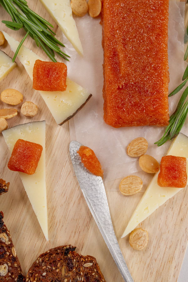 looking down on a cheese plate with some quince paste on it.
