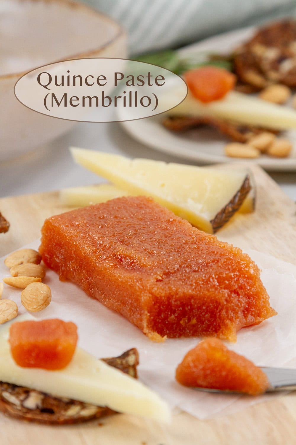some quince paste in a rectangle with cheese, crackers, and herbs around it.