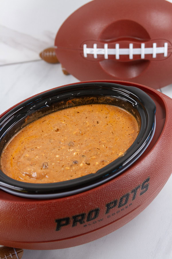a football shaped slow cooker with dip in it.