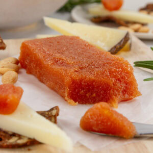 square crop of a cube of quince paste on a cheese plate with a spreader.