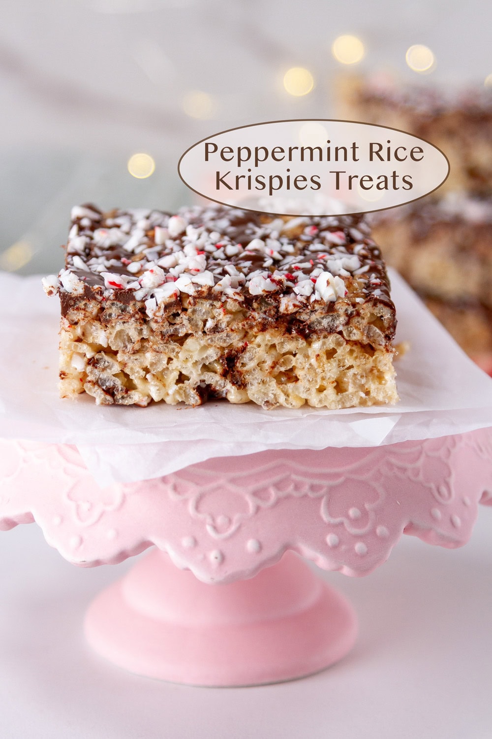 a Peppermint Rice Krispies Treats on a small pink serving tray with twinkle lights in the background.