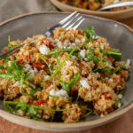 square crop of a bowl of salad with a fork in the back.