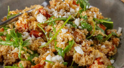 square crop of a bowl of salad with a fork in the back.